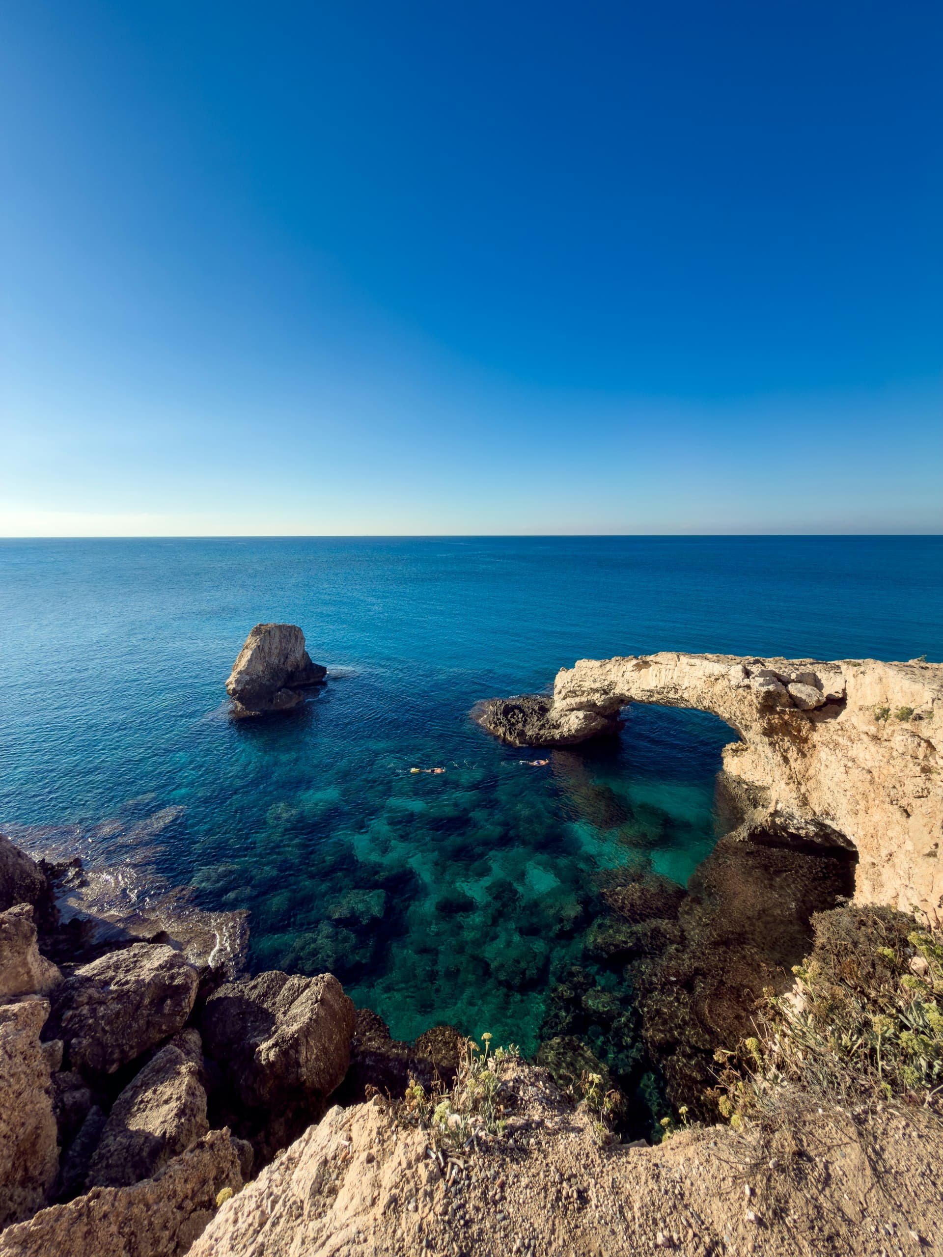 A natural rock arch over clear turquoise sea water